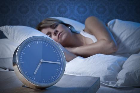 Woman sleeping soundly next to an alarm clock.