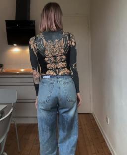 Person with elaborate back tattoo wearing jeans.
