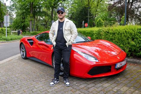 Luca Brecel, snooker world champion, posing with a red Ferrari.