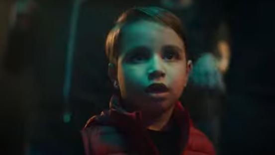 Screenshot of a young boy in a red jacket, looking concerned.