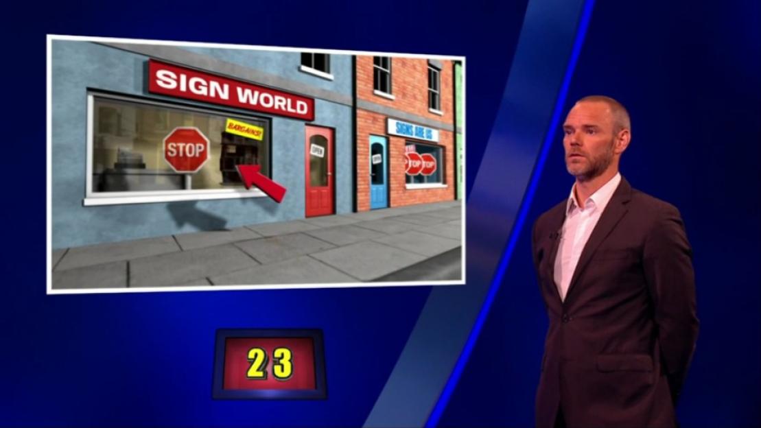 Joe Absolom on Celebrity Catchphrase, pointing to a shop window.