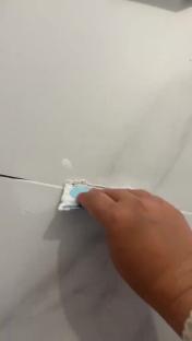 Hand applying filler to a crack in a wall.