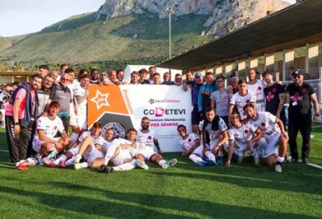 Soccer team posing with a sponsor's sign.