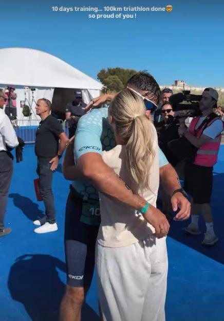 A woman embraces a man after he completes a 100km triathlon.