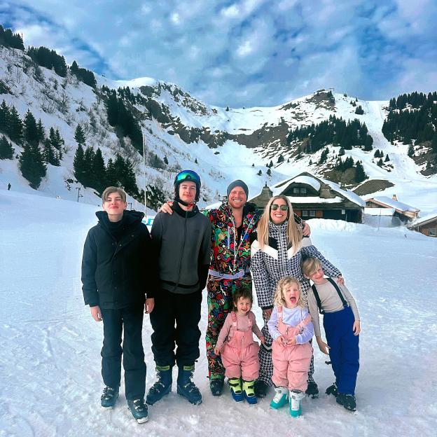 Family in ski gear posing in snowy mountains.