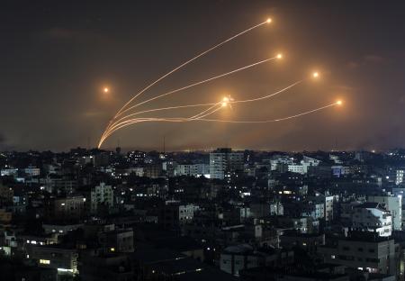 Missiles launched from Gaza over a city at night.