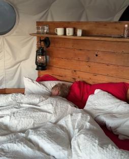 Child sleeping in a bed with white bedding.