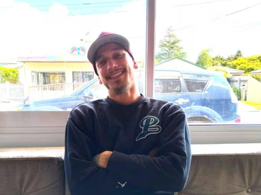 Photo of a smiling man sitting with his arms crossed.