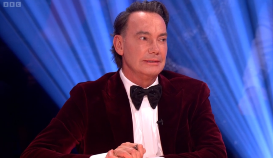 Craig Revel Horwood wearing a red velvet jacket and black bow tie.