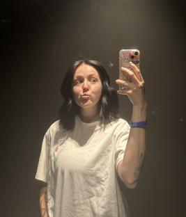 A young woman with dark hair takes a selfie.