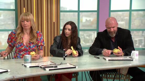 Three people peeling potatoes at a table.