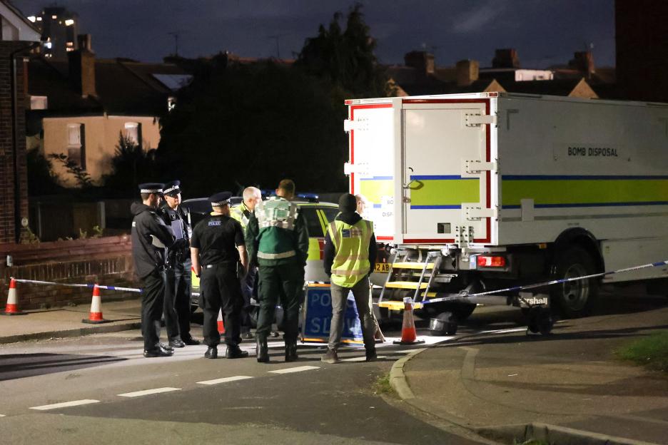 Emergency services personnel gathered at night around a bomb disposal truck.