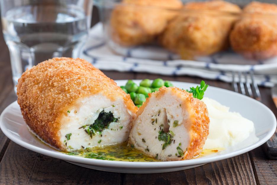 Chicken Kiev cutlet with mashed potatoes and peas.