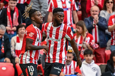Two soccer players celebrating in front of spectators.