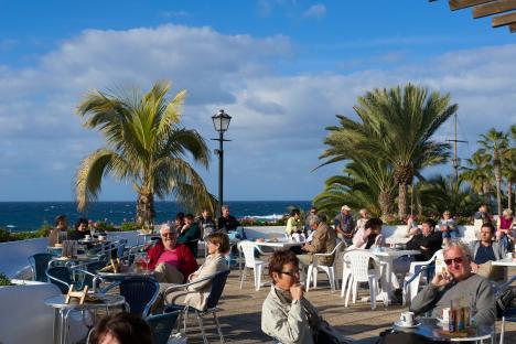 Patrons at an outdoor cafe overlooking the ocean.