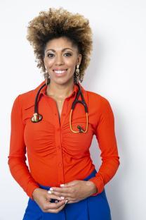 Portrait of Dr. Zoe, a columnist, wearing a red shirt and blue pants. She is smiling and has a stethoscope around her neck.