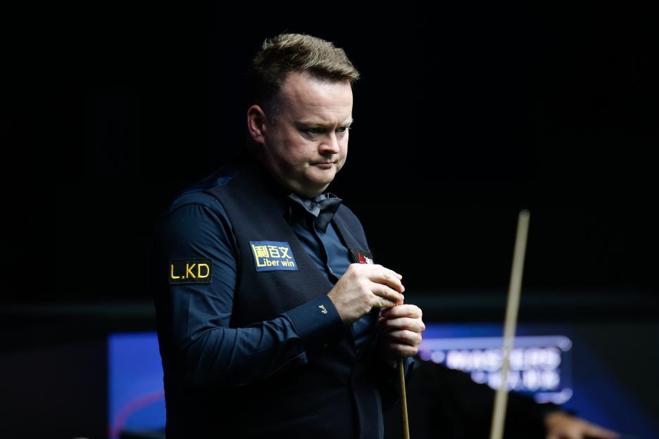 Shaun Murphy chalking his cue at a snooker match.