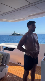 Man on a yacht deck putting on shorts.