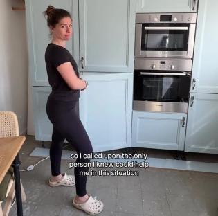 Woman standing in a kitchen with light blue cabinets and stainless steel appliances.