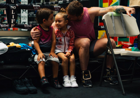 A man sits with two young children.