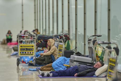 People sleeping on the floor of an airport terminal.