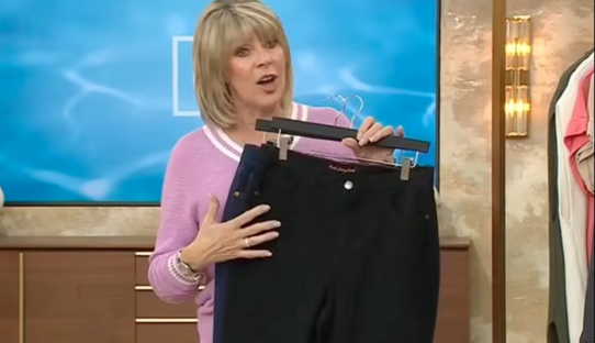 Ruth Langsford holding up a pair of black pants on a hanger.