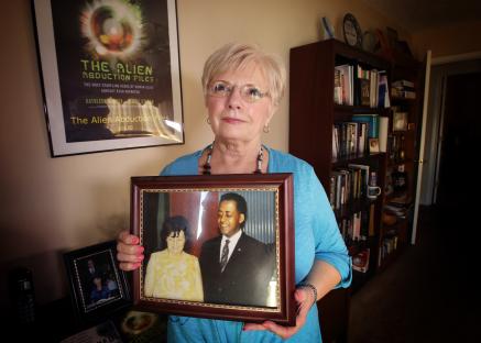 Woman holding a framed photo of her aunt and uncle, known for their alleged alien abduction.