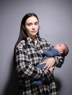 A woman in a plaid shirt holds a baby.