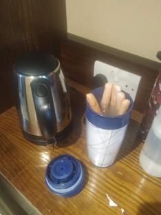 A kettle and travel mug with fingers soaking in water.