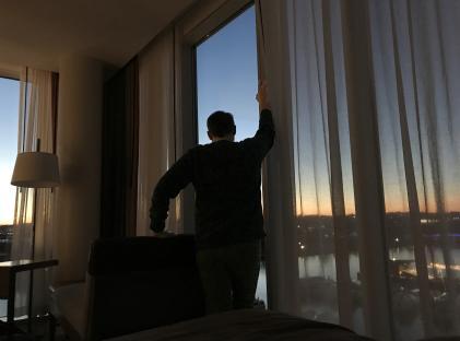 Man silhouetted against sunset view from hotel window.
