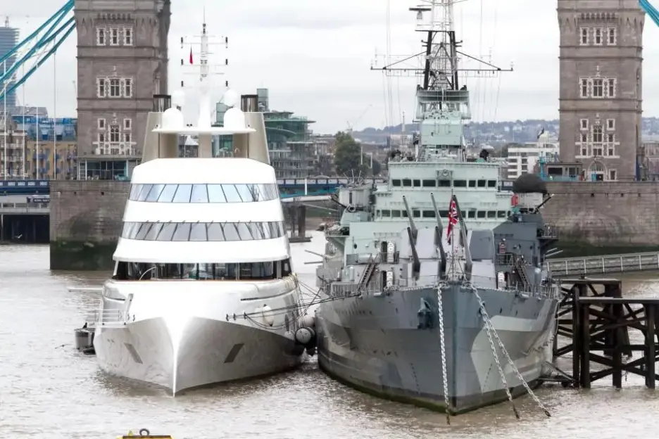 The superyacht "Symphony" moored next to HMS Belfast, with the Tower Bridge in the background.