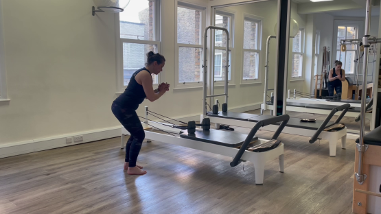 Woman doing Pilates leg exercises on reformer.