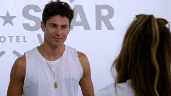 Screenshot of a man in a white tank top being interviewed.