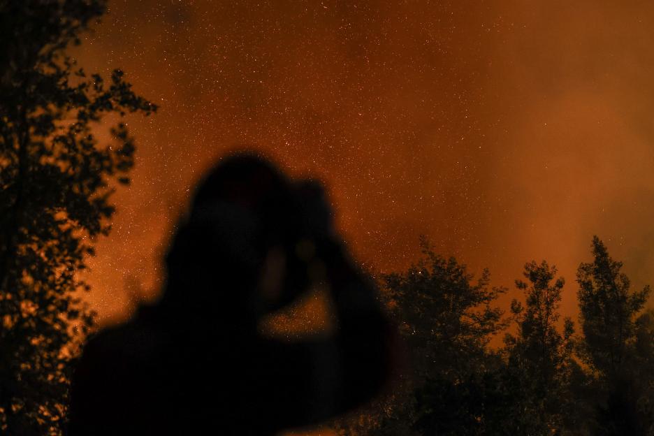 Silhouette of a firefighter against a backdrop of a forest fire.