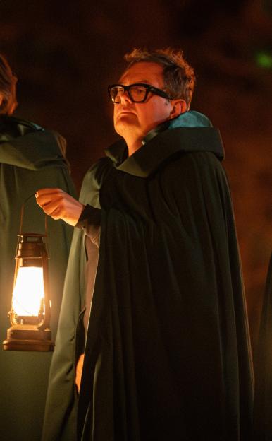 Three "Traitors" contestants holding lit lanterns in the dark.