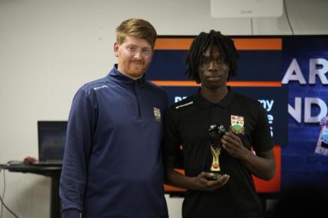 A young man receives an award from a coach.