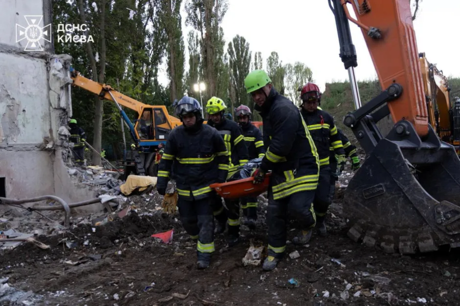Firefighters carrying a stretcher from a damaged building.