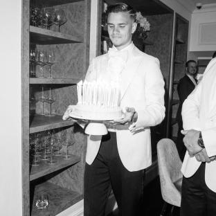 Black and white photo of a man holding a birthday cake.