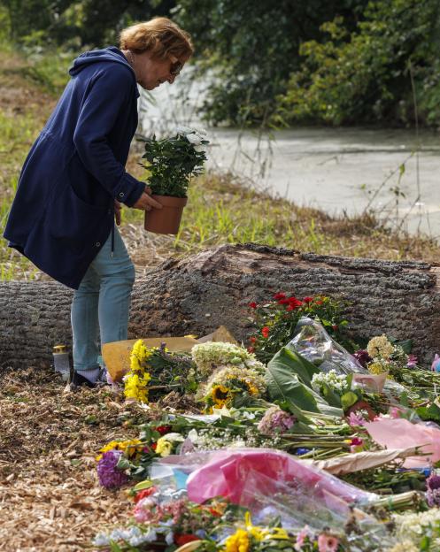 Woman adding flowers to a memorial.