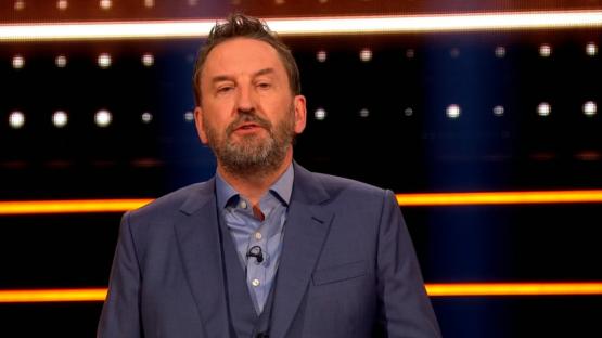 A man in a suit on a game show set.