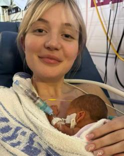 Mother holding newborn baby in hospital bed.
