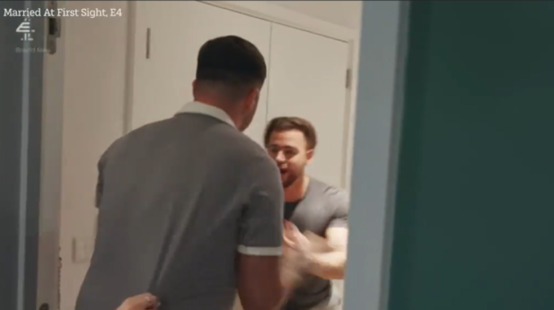 Two men engaged in a heated altercation, being held back by an unseen person.