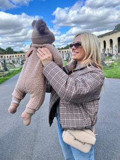 Woman holding baby in cemetery.