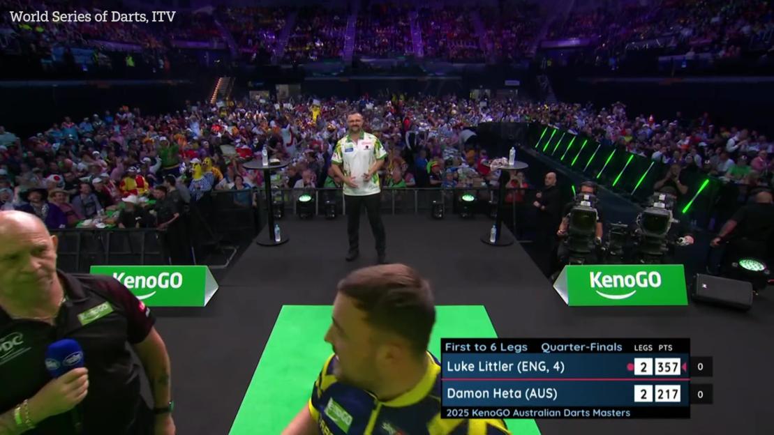 Luke Littler reacting to the crowd at a darts match.