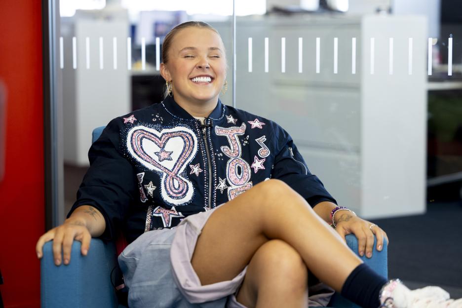 JoJo Siwa smiling and sitting in a chair.