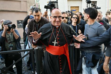 A cardinal surrounded by photographers and reporters.