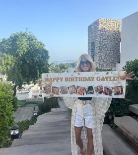 Woman holding a birthday banner for Gayle.