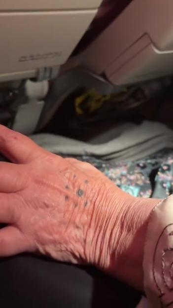Close-up of a hand with a small tattoo on the back, on an airplane.