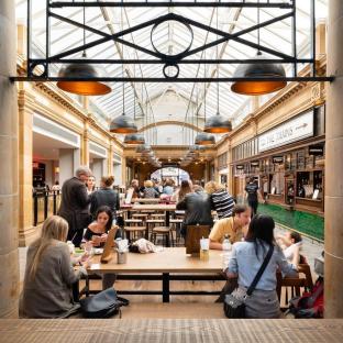 People eating at tables in a market hall.