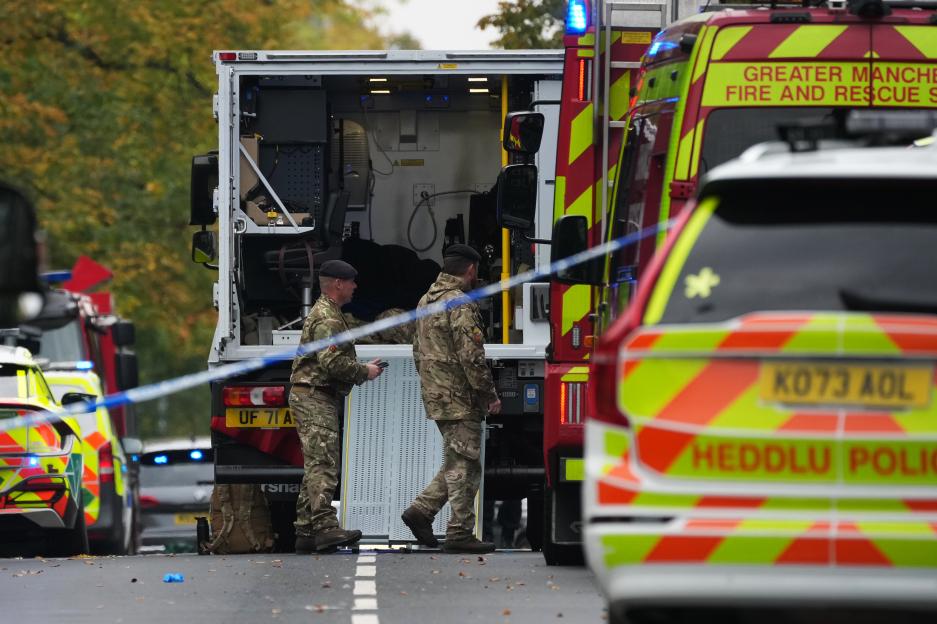 Military personnel at a crime scene with police and fire vehicles in Crumpsall, Manchester, England.